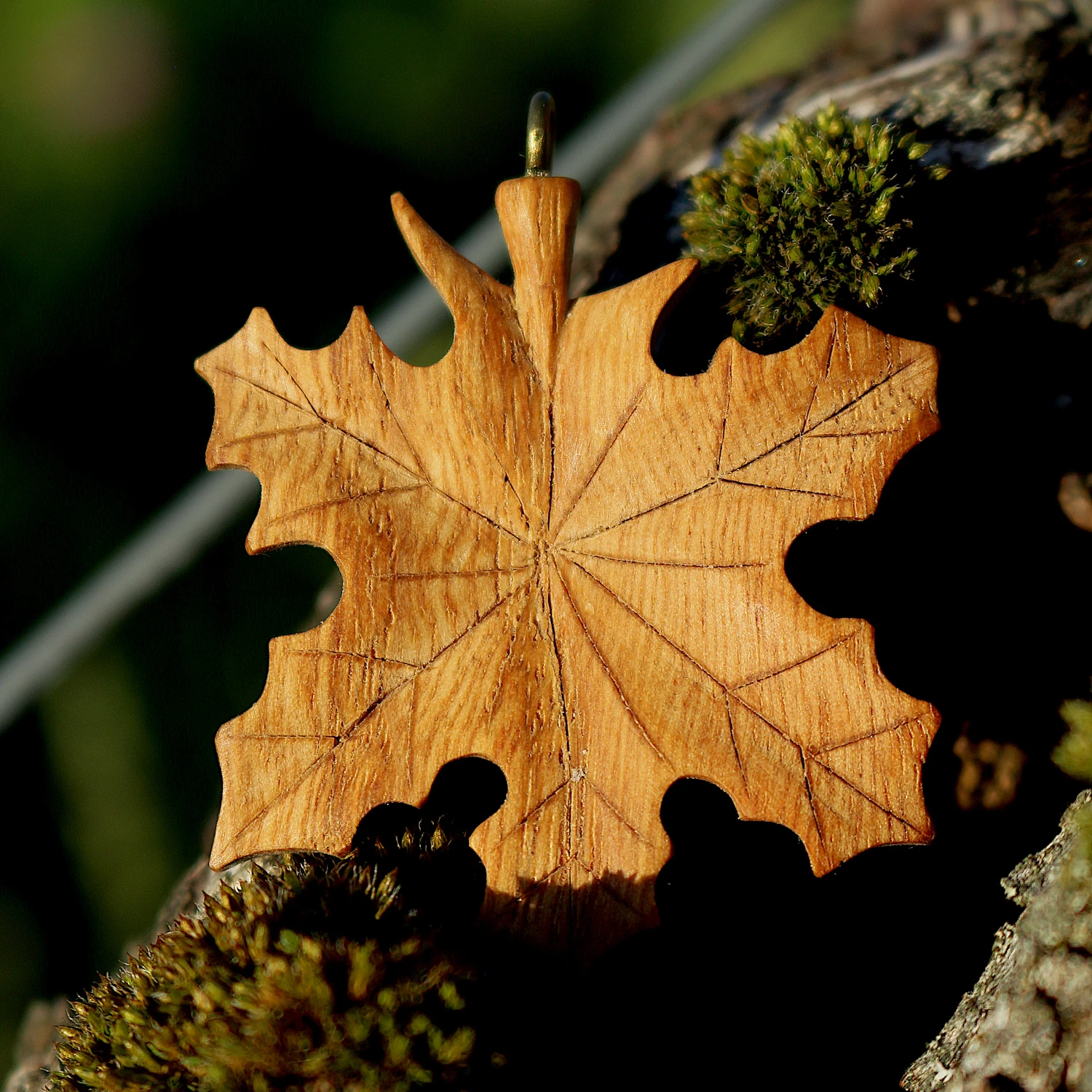 Handgeschnitztes Ahornblatt aus Kastanienholz in der Natur, unscharfer Hintergrund, warmes Licht – Handarbeit, Ruhe, Naturverbundenheit