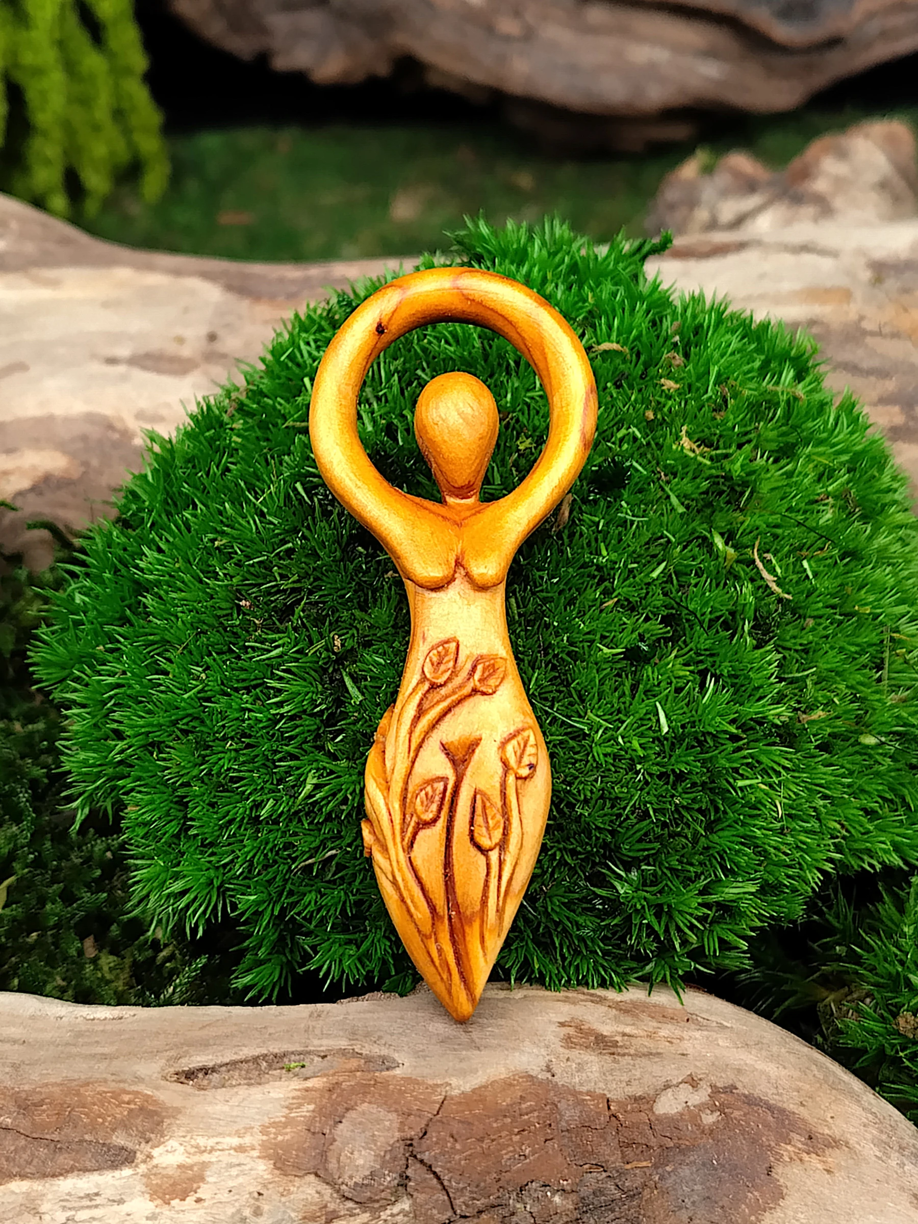Handgeschnitzte Göttinnenfigur aus Holz mit Blattranken, spiritueller Holzanhänger als Kraftsymbol für Naturverbundenheit, Weiblichkeit und innere Stärke, fotografiert auf Moos und Holz.